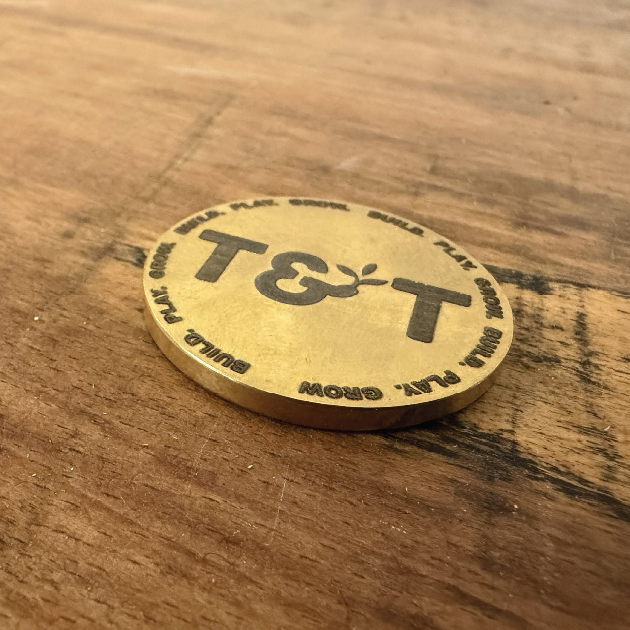Tog & Twig logo engraved onto a brass coin at Cobblestone Creative.